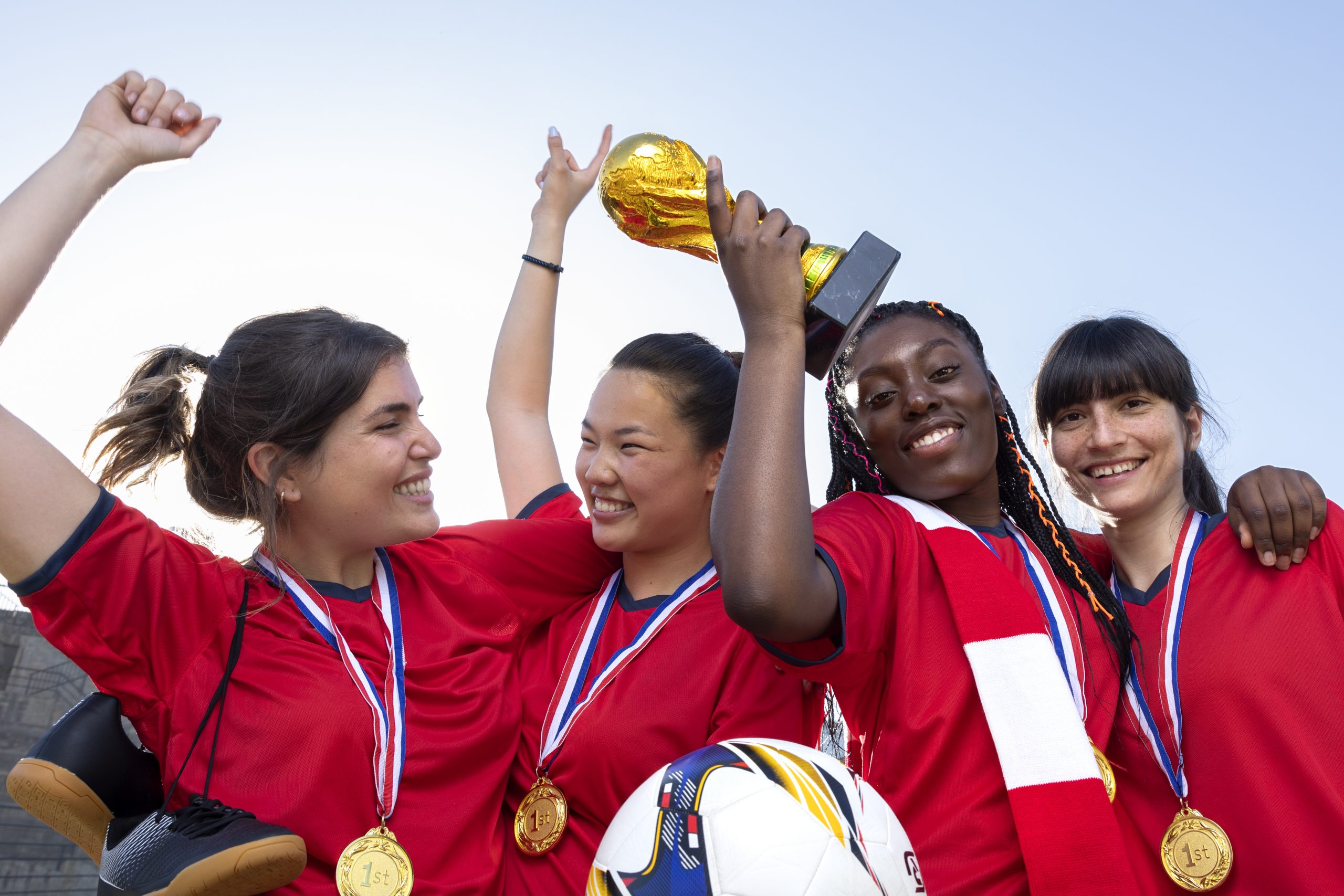 Youth sports team celebrating a win with a silver cup trophy, symbolising teamwork and achievement.